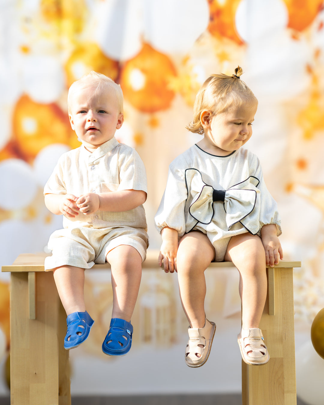 mace and co kids clothing dubai, linen romper with long sleeves and a bow on the front, for girls ages infant, toddler and up to seven years old. Pictured with the boys linen shirt and shorts set. Both outfits perfect for formal occasions, birthday parties and playtime.
